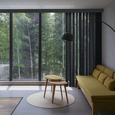 a living room with a couch, coffee table and large glass windows that look out onto the woods