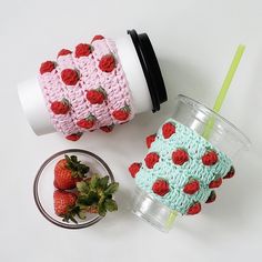 two cups with strawberries on them are next to a strawberry cup cozyie and a drink holder