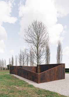 a large metal sculpture sitting on top of a lush green field next to a tree