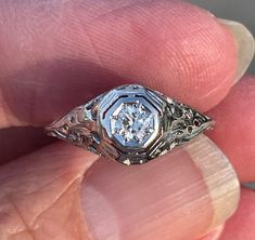 a close up of a person's hand holding an old - fashioned diamond ring