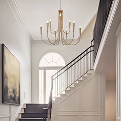 a hallway with stairs and chandelier in it