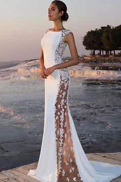 a woman in a white and brown dress standing on a dock