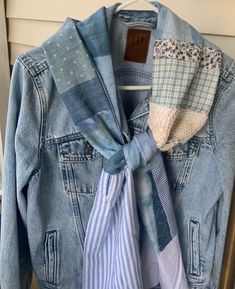 an old jean jacket is hanging up on a hanger with some fabric pieces attached to it