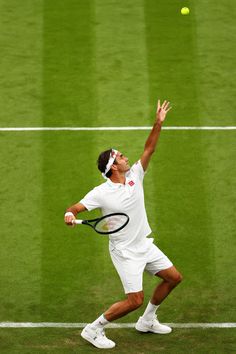 a tennis player is reaching up to hit the ball with his racket on a grass court