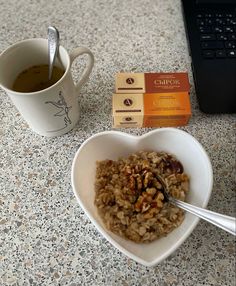 a heart shaped bowl filled with oatmeal next to a cup of coffee