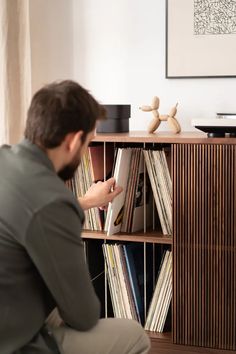 a man sitting in front of a book shelf filled with records