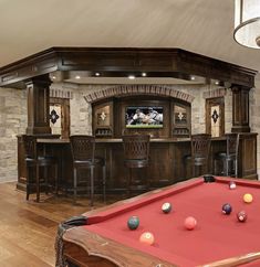 a pool table in front of a bar with stools and a television mounted to the wall