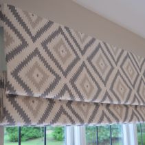 a window with roman blinds in front of it and an open window behind the blind