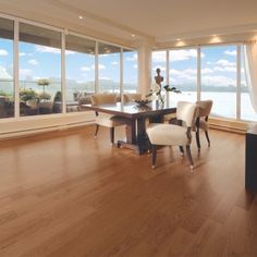 a dining room table and chairs with large windows overlooking the water in front of them