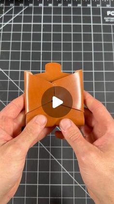 someone is holding an origami piece with a video playing button in the middle