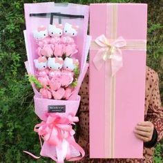 a woman is holding a pink box with hello kitty decorations on it and a bouquet of flowers in front of her