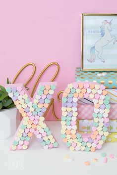 the letter k is made out of confetti and plastic beads, next to a box with a unicorn on it