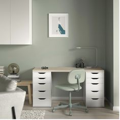 a white desk with drawers and a chair in a room that has light green walls