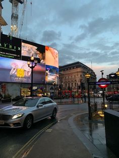 a car is parked on the street in front of a large billboard that has been lit up