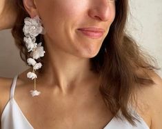 a woman wearing large white flowers on her earrings