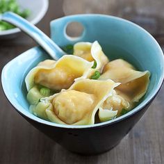 a blue bowl filled with dumplings on top of a wooden table