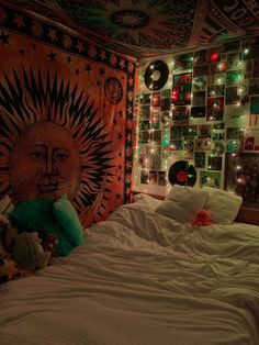 a bed with white sheets and lights in a room that has a tapestry on the wall