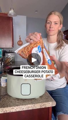 a woman sitting on a kitchen counter holding a bag of cheeseburger potato casserole