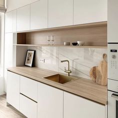 a kitchen with white cabinets and wooden counter tops, including a gold faucet