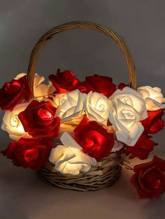 a basket filled with lots of red and white flowers next to a lit up candle