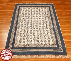 a blue and white rug with fringes on top of a wooden floor in a room