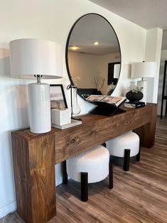 a mirror sitting on top of a wooden table next to two stools and a lamp