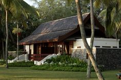 the house is surrounded by palm trees and grass