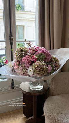 a bouquet of pink and white flowers sitting on top of a table next to a window