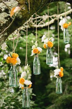 hanging mason jars filled with white and yellow flowers are the perfect way to add color to an outdoor ceremony