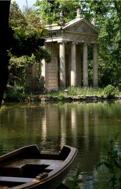 there is a boat on the water in front of a building with columns and pillars