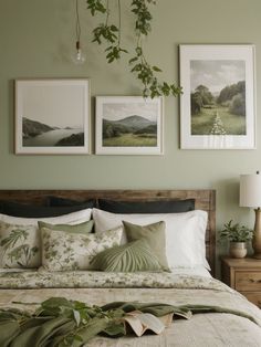 a bedroom with green walls and pictures on the wall above the bed, along with plants