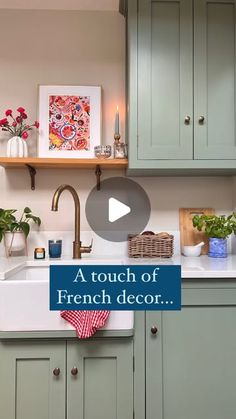 a kitchen with green cabinets and a white sink in front of a wooden shelf filled with potted plants