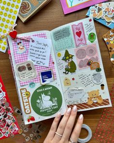 a person holding an open book on top of a table with lots of stickers