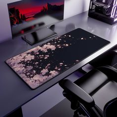 a computer desk with a mouse pad and monitor on it, next to a black chair