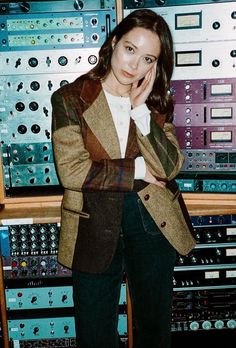 a woman standing in front of an array of sound mixing equipment with her hand on her chin