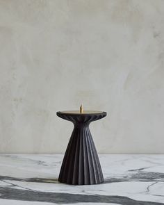 a black candle holder sitting on top of a marble table