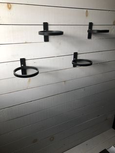 three black metal hooks on the side of a white wall