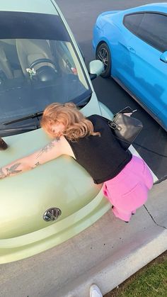 a woman leaning on the hood of a car