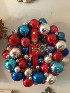 a christmas wreath made out of red, blue and silver ornaments with a nutcracker in the middle