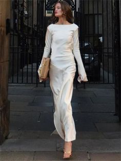 a woman in a white dress is walking down the street