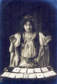 an old photo of a woman sitting at a table with cards in front of her