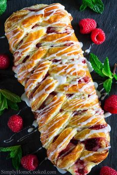 a croissant with raspberries and cream drizzled on top