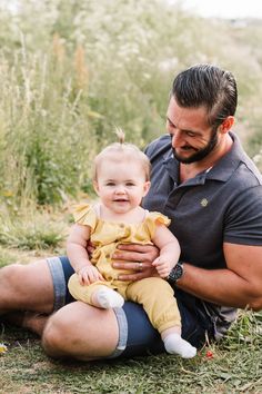 a man holding a baby while sitting on the ground