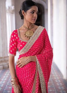 This look features a raspberry pink banarasi saree set. The flowy georgette has woven gold motifs with handcrafted sequin, mirror and pearl border. A matching embellished scoop neck blouse completes the look. Includes a satin underskirt Composition: Blouse - Viscose georgette, Saree - Viscose georgette , Underskirt - Satin Care: Dry Clean Only and Vacuum Storage This product can be customised for colour, sleeves, length of blouse and neck design Delivery : 2 weeks as the product is hand crafted. For more information and sizes please contact fabiliciousfashion@gmail.com or visit our Copenhagen studio. About the Designer : Renee Label was created in 2013,by the talented sister duo Pooja and Karuna, is a culmination of their love for fashion and art. The mesmerizing wedding wear collection th Festive Gota Work Georgette Blouse, Festive Gota Work Blouse With Traditional Drape, Festive Blouse With Gota Work And Traditional Drape, Festival Gota Work Georgette Blouse, Festive Reception Blouse With Zari Weaving, Festive Blouse With Zari Weaving For Reception, Festive Traditional Drape Blouse With Gota Work, Transitional Pink Saree With Mirror Work, Gold Georgette Blouse With Cutdana