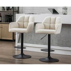 two white bar stools sitting on top of a wooden floor next to a counter