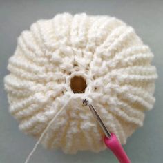 a white ball of yarn with a pink crochet hook