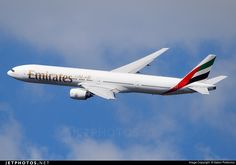 an emirates airplane flying in the sky on a clear day with some clouds behind it