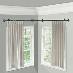 two windows with white curtains in front of them and one has a black metal rod