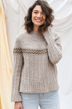 a smiling woman wearing a sweater and jeans