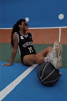 a female basketball player sitting on the ground with her foot up and ball in front of her